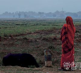 女人站在路边，看着自己的村庄。
